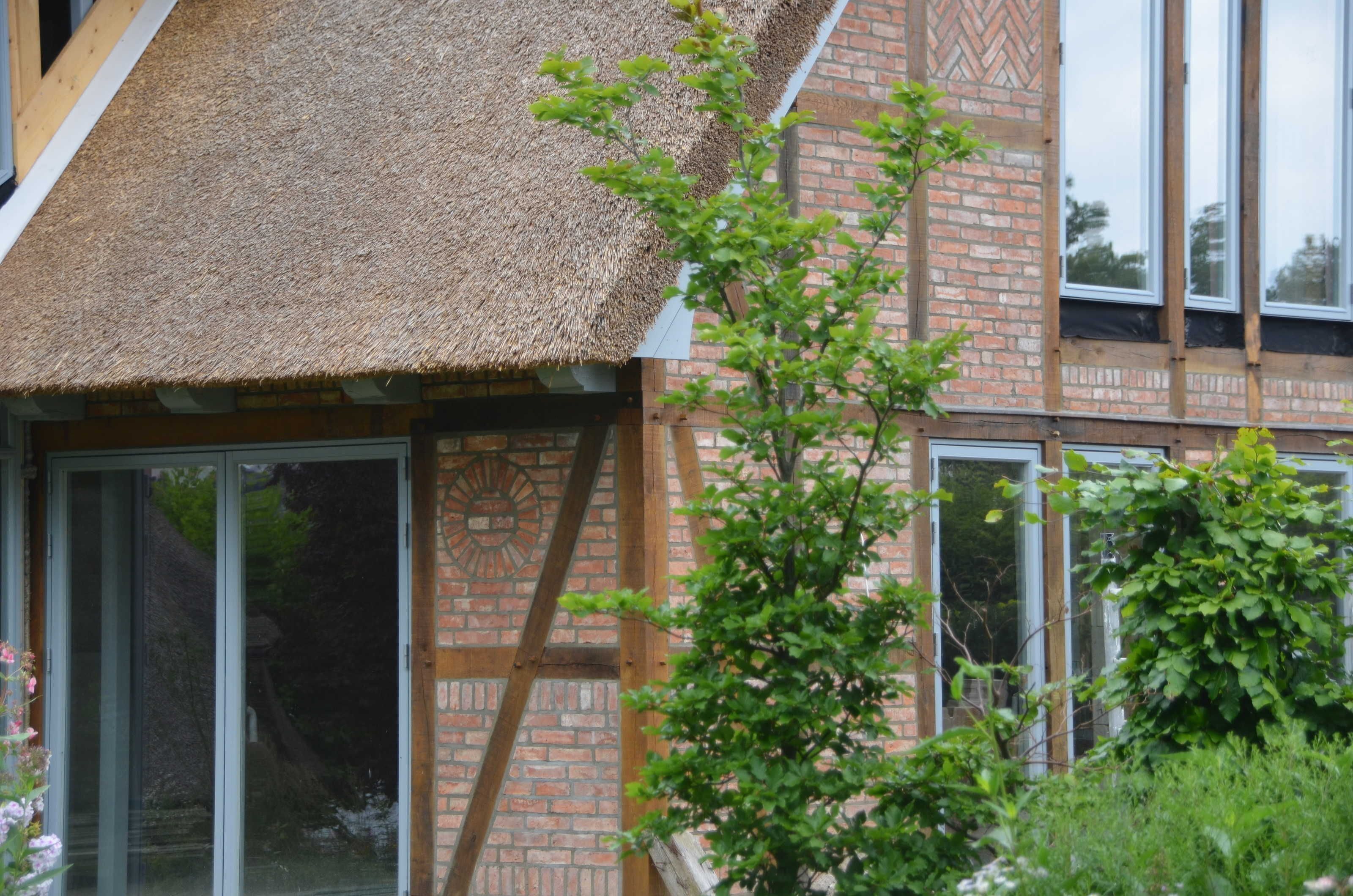 A building with a thatched roof, brick walls, and large windows.