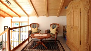 A wooden-floored room with two upholstered chairs, a round table, and a wooden cabinet. - Bischof Reingard - Apartment 2 1 (Schoppernau)
