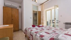 A bedroom with a bed, a wooden wardrobe, a desk, and a bathroom visible through an open door. - Gorgeous apartment in Lovrecica with WiFi (Lovrecica)