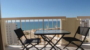 A balcony with a glass table and two chairs, overlooking a beach and the sea. - TOP - APARTMENT VISTA PRAIA WITH FANTASTIC SEA VIEWS (Armacao de Pera)