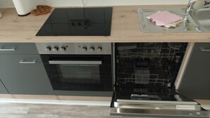A kitchen with a built-in oven, dishwasher, and a black induction cooktop. - Apartment I. First floor 82sqm, 2 bedrooms with balcony - Old Fire Station Görlitz City (Görlitz)