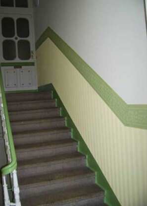 A staircase with green railings and a white door with glass panels.