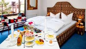 A hotel room with a neatly made bed, breakfast table with various food items, a chair, and a view of the outdoors. - Comfort double room with terrace - artHOTEL Magdeburg GmbH (Magdeburg)