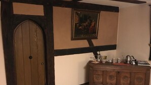 A room with a wooden door, a painting on the wall, and a wooden cabinet with various items on top. - McMüller's Kemenate Fulda (Fulda)