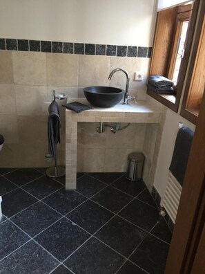 A compact bathroom with a black sink, a towel rack, a toilet, and a small trash bin. - McMüller's Kemenate Fulda (Fulda)