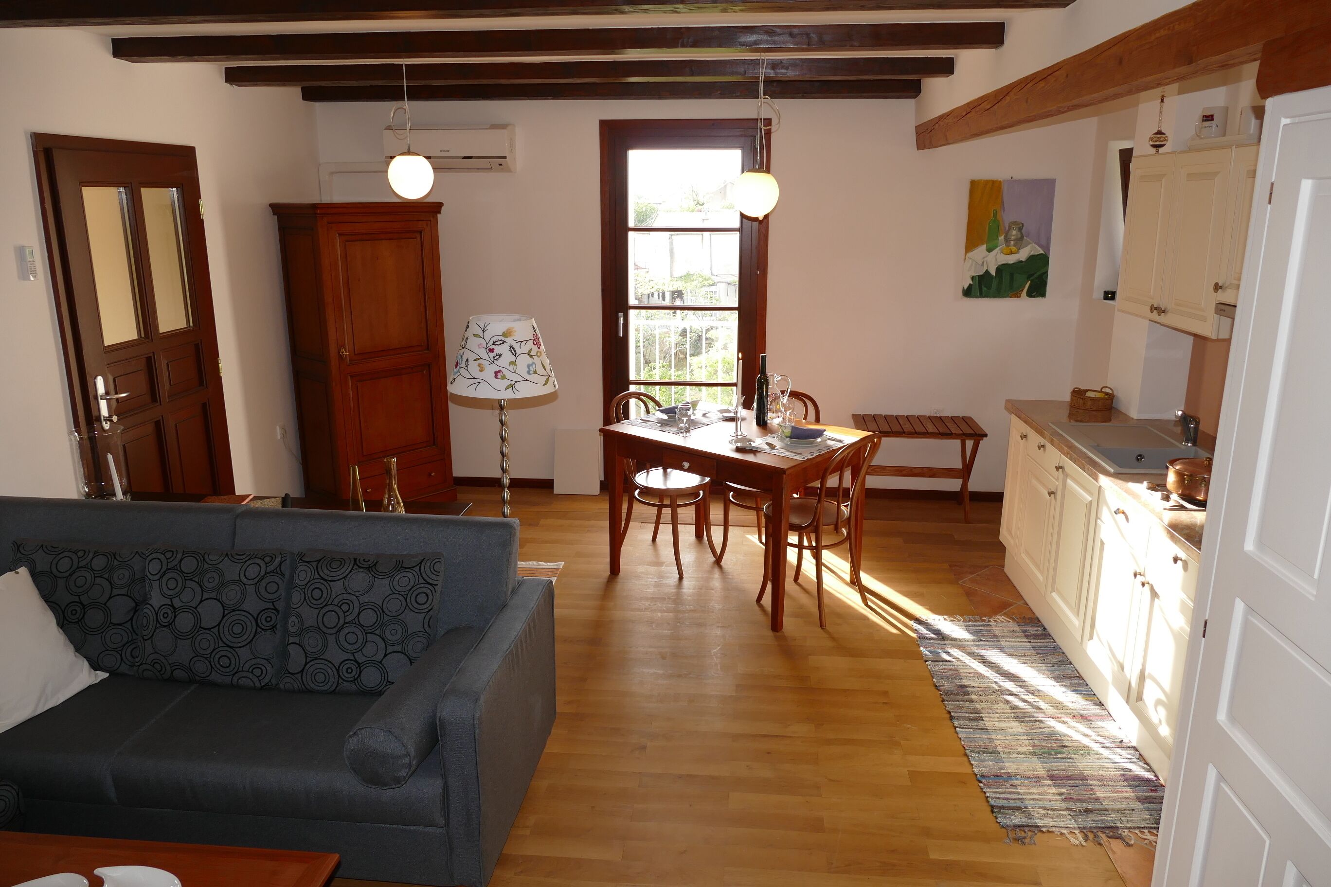 Ein gemütliches Wohnzimmer mit Sofa, einem Esstisch mit Stühlen, Holzschränken und einer Küchenzeile mit Arbeitsplatte.