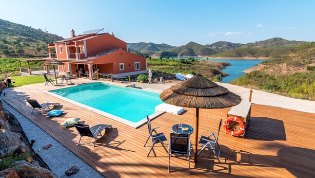 A villa with a swimming pool, deck chairs, and a thatched umbrella. - Luxurious villa with pool and idyllic lake landscape (Silves)