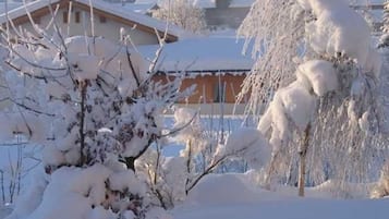 A snow-covered landscape with a building that has a sloped roof and a visible window.