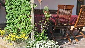 Ein Holzhocker, eine herzförmige Dekoration und ein Holzpflanztopf mit Pflanzen.