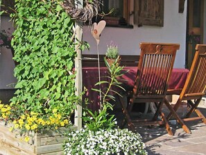 A wooden chair, a heart-shaped decoration, and a wooden planter with plants.