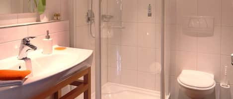 A bathroom with a glass-enclosed shower, a white sink, and a toilet.
