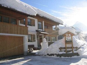 Ein hölzernes Gebäude mit schneebedecktem Dach, einem Schild mit der Aufschrift 'Hotel Evelin' und einer Schneemann-Dekoration.