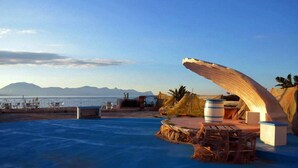 A pool area with a wooden deck, a large curved structure, and a view of the sea and mountains in the background. - Nice Casa Andrea with beautiful panoramic views of the sea (Balestrate)