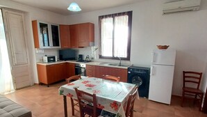 A compact kitchen with wooden cabinets, a dining table with chairs, a washing machine, and a refrigerator. - Nice Casa Andrea with beautiful panoramic views of the sea (Balestrate)