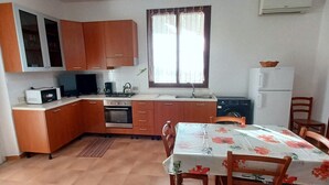 A compact kitchen with wooden cabinets, a dining table with chairs, and a built-in oven. - Nice Casa Andrea with beautiful panoramic views of the sea (Balestrate)