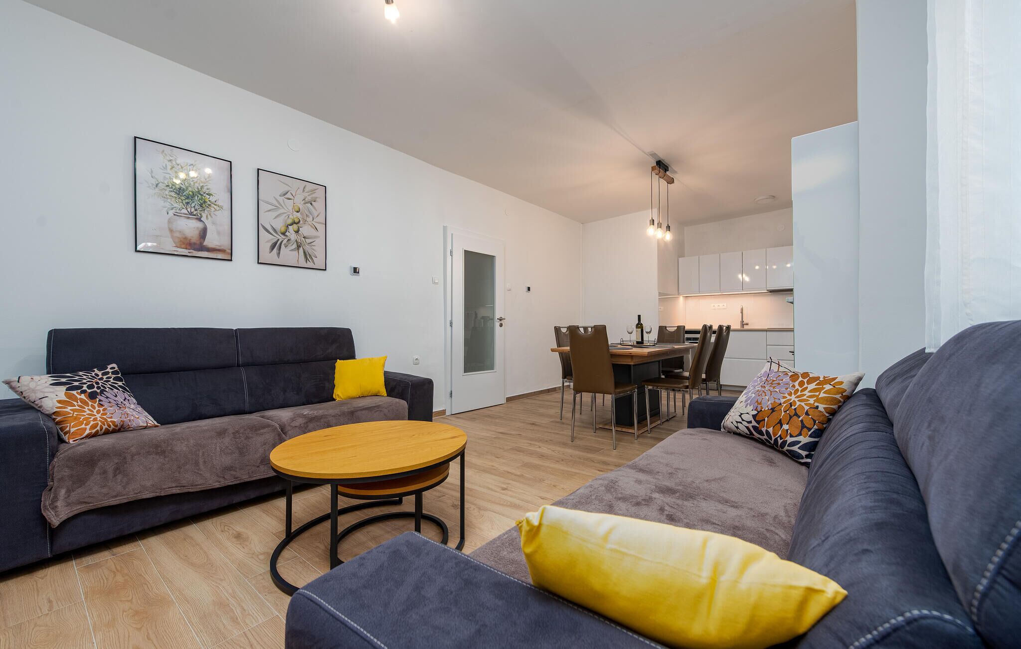 Een moderne woonkamer met een bank, een ronde salontafel en een eethoek met stoelen en een tafel.