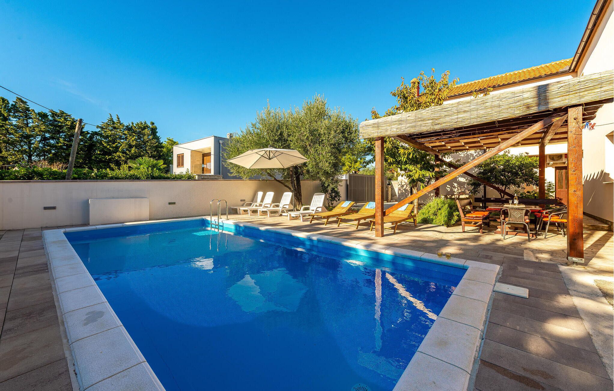Piscina com espreguiçadeiras e um pergolado.