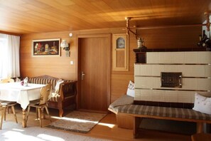 Un intérieur en bois comprenant une table à manger, des chaises, un banc, une horloge et une cheminée.