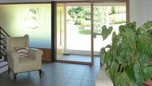 Une pièce comprenant une chaise, une plante en pot et une porte-fenêtre coulissante donnant sur un espace extérieur.