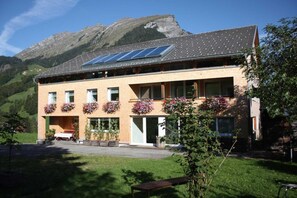 Un bâtiment à deux étages, doté d’un toit en pente, de panneaux solaires et de jardinières aux fenêtres.