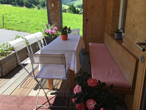 Eine Holzterrasse mit einer Bank, einem Tisch und Stühlen.