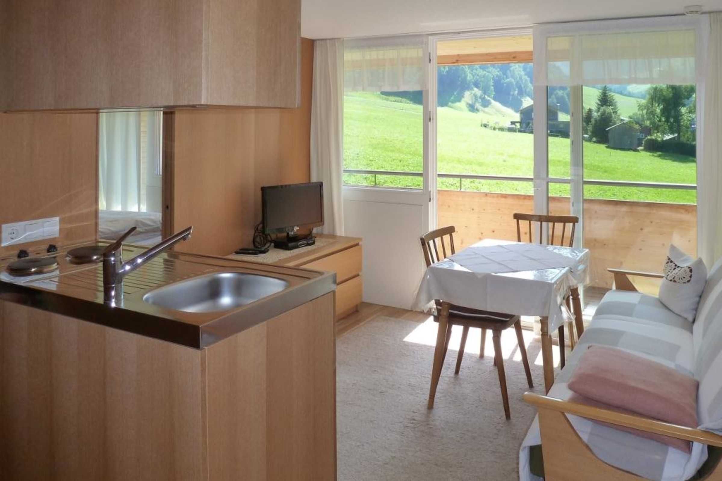Une cuisine compacte comprenant un évier, une cuisinière et un coin repas avec une table et des chaises.