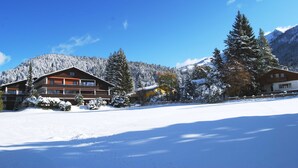 A lodge with a large snow-covered yard and mountains in the background. - Luxury Apartment Alpenblick ***** - Berghaus Tirol (Seefeld in Tirol)