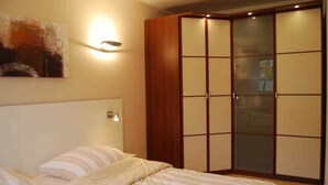 A bedroom with a bed, a wardrobe, and a wall-mounted light fixture. - Luxury Apartment Alpenblick ***** - Berghaus Tirol (Seefeld in Tirol)
