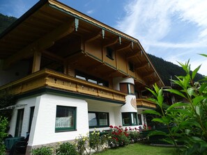 Een klassiek chalet met een houten gevel, witte muren en een balkon.