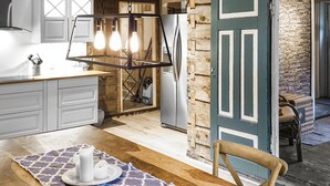 A kitchen with white cabinets, a wooden countertop, hanging pendant lights, and a rustic door.