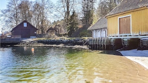 A riverside scene with a wooden building, a stone wall, and a clear water body.