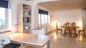 Un salon moderne avec une table en bois, des chaises, une bibliothèque et une fenêtre.