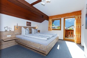 A bedroom with a wooden bed, a nightstand, a headboard with a mirror, and a window with curtains. - Apartment 1 - House Maringele (Nesselwängle)