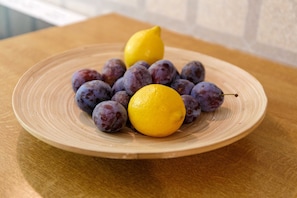 Un plato con ciruelas y un limón sobre una mesa de madera.