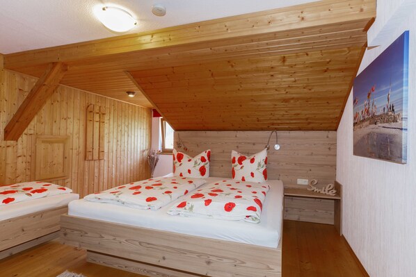 Une chambre à coucher dans un chalet en bois, avec un lit, deux tables de chevet, une lampe fixée au mur et un tableau.