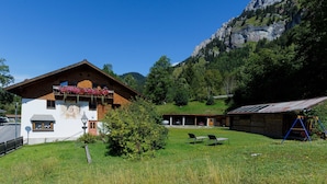 Un chalet de montagne à la façade blanche, doté de balcons en bois et surplombant un paysage montagneux.