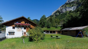 Un chalet de montagne à la façade blanche, doté de balcons en bois et surplombant un paysage montagneux.