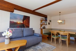 Una sala de estar con un sofá, una mesa de madera, un banco y una estantería.