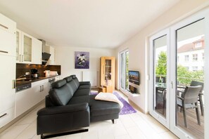 A modern apartment with a living area, kitchen, and balcony.