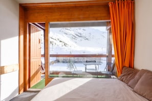 A bedroom with a large window overlooking a snowy mountain landscape.