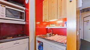 A compact kitchen with a microwave, stove, sink, and wooden cabinets.
