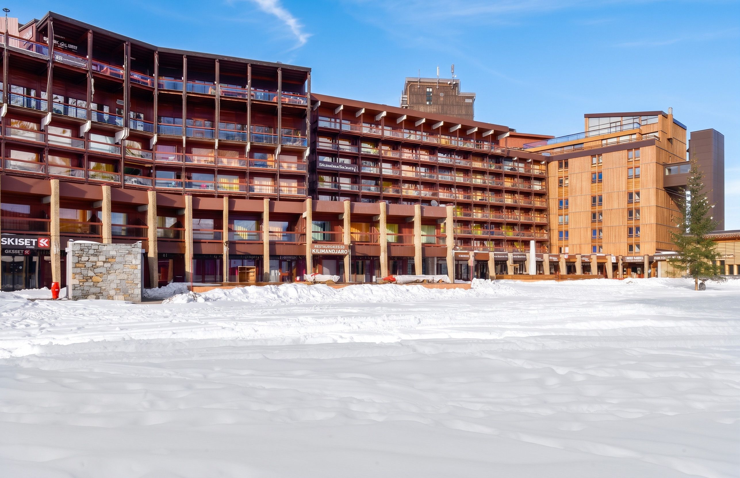A multi-story hotel with a central atrium and balconies, surrounded by snow.