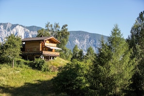 A wooden cabin with a balcony, surrounded by trees and mountains. - Vacation apartment cat. 1 1 - Aktiv-Ferienwohnungen Pienz-Bobnar (Sautens)