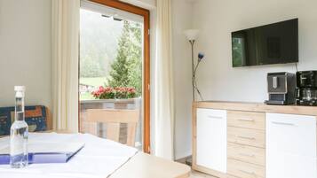 Eine moderne Küche mit Flachbildfernseher, Kaffeemaschine und Blick ins Grüne.