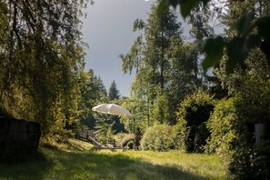 A garden with a white umbrella, a wooden bench, and a stone wall.