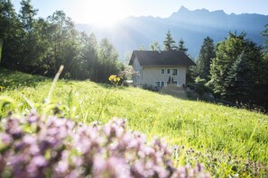 A house on a grassy hill with mountains in the background. - Vacation apartment cat. 1 1 - Aktiv-Ferienwohnungen Pienz-Bobnar (Sautens)