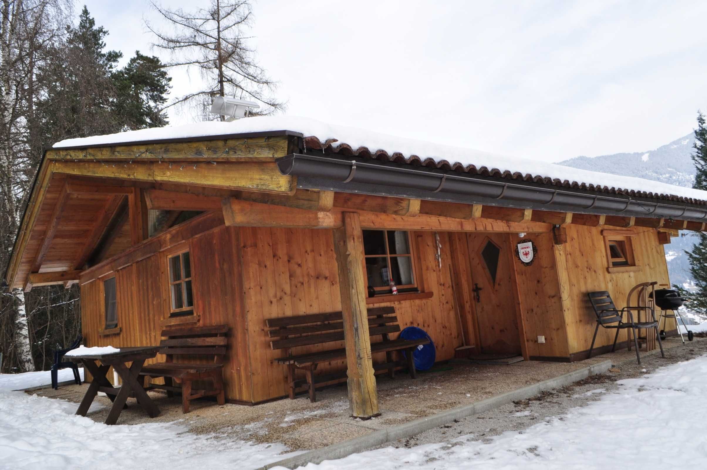 Eine Holzhütte mit einer Veranda, Bänken und einem Tisch.