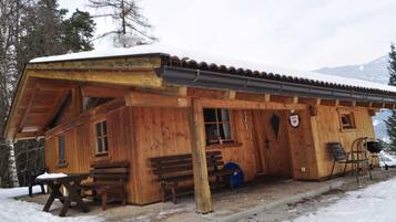 Eine Holzhütte mit einer Veranda, Bänken und einem Tisch.