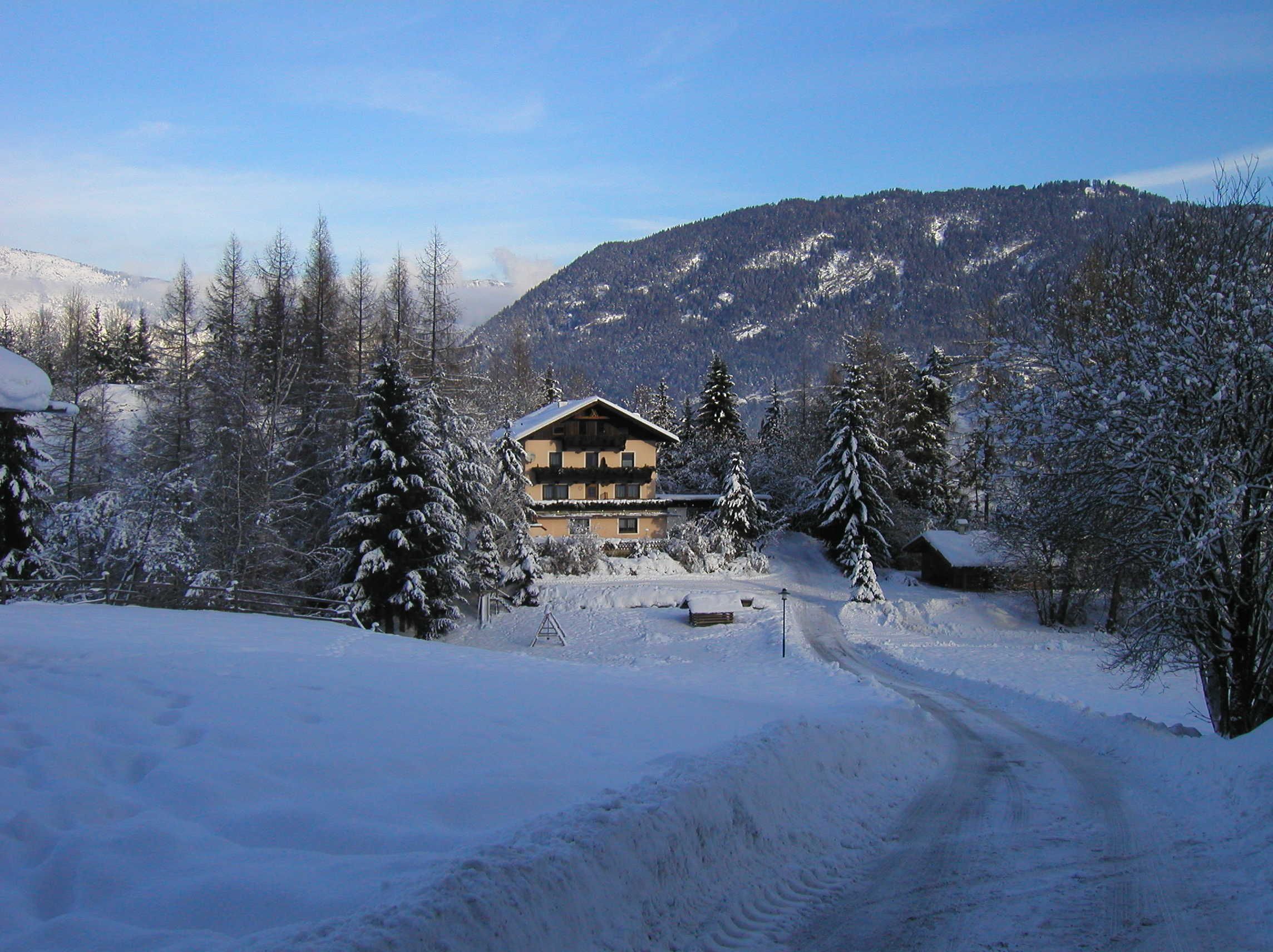 Un paysage montagneux enneigé avec un chalet doté d’une façade en bois et d’un balcon.