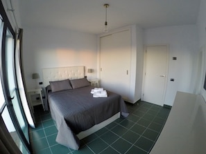 A hotel room with a bed, nightstands, a wardrobe, and a window.